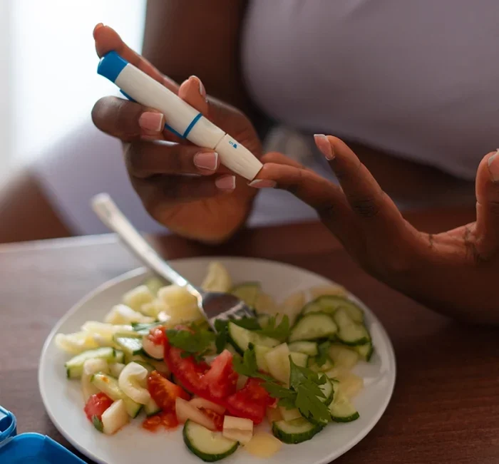 A person checking blood sugar beside a fresh vegetable salad, the everyday context SugarReset is used in